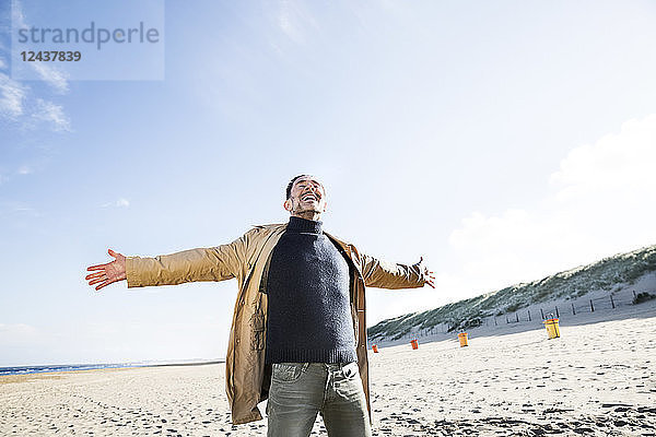 Happy man standing on the beach with outstretched arms