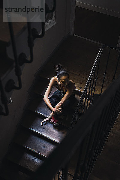 Beautiful young woman sitting in staircase in sunlight