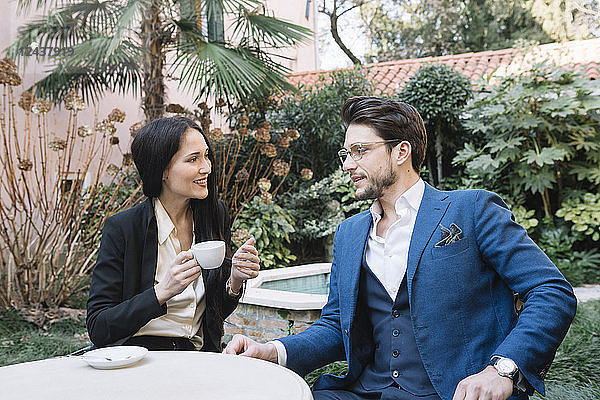 Elegant couple talking in a garden cafe