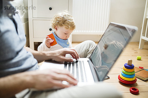 Father at home with his little son using laptop