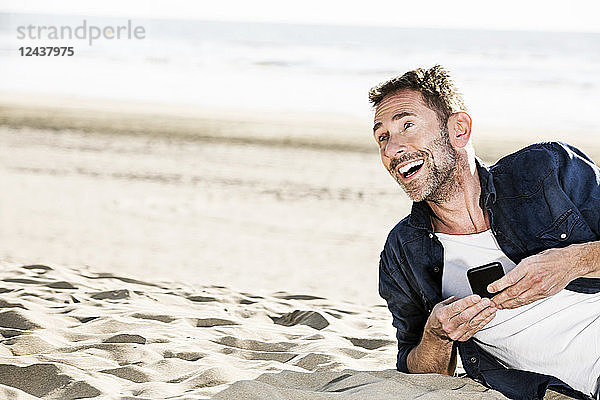 Happy man with cell phone on the beach