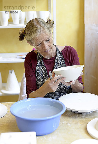 Woman working on bowl in porcelain workshop