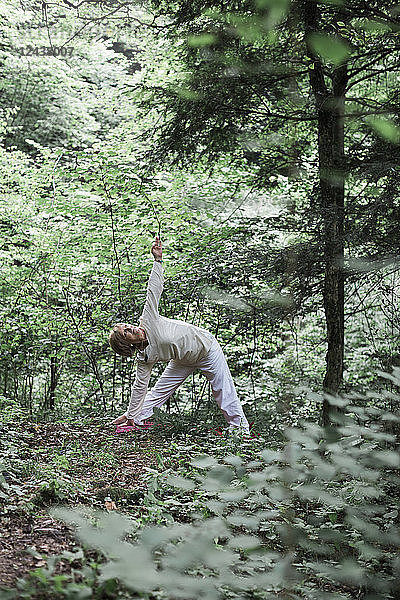 Senior woman doing yoga in the forest  triangle pose