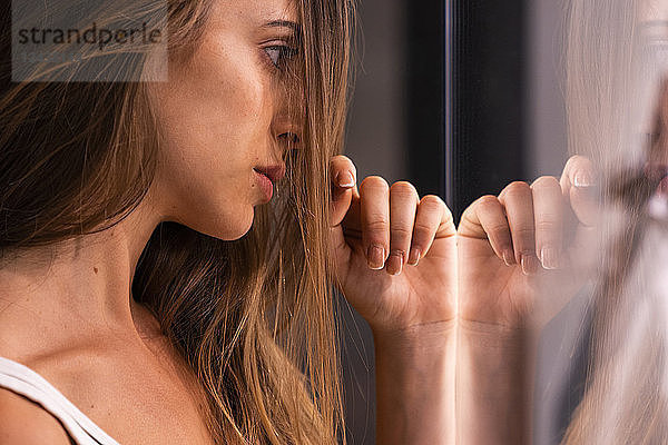 Serious attractive young woman leaning against glass pane