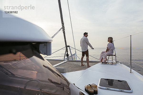 Mature couple standing on catamaran trampoline  enjoying their sailing trip