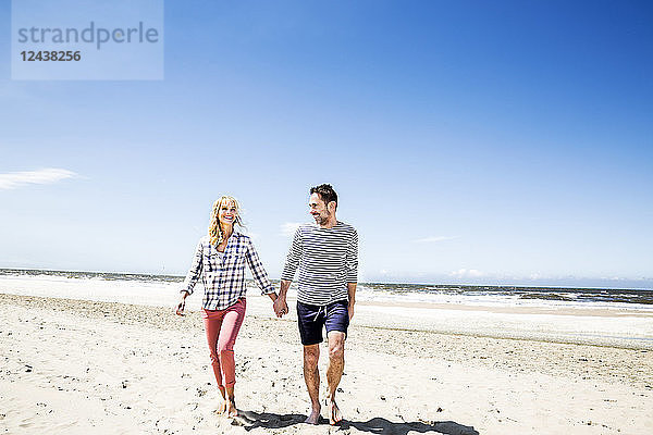 Couple walking hand in hand on the beach