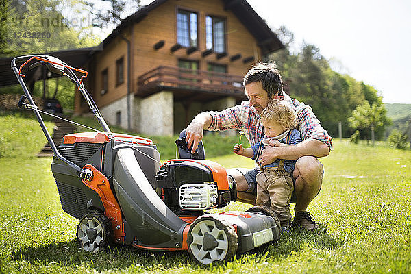 Father with his little son and lawn mower