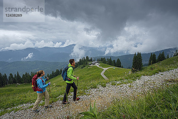 Germany  Lenggries  young couple with hiking poles hiking upwards