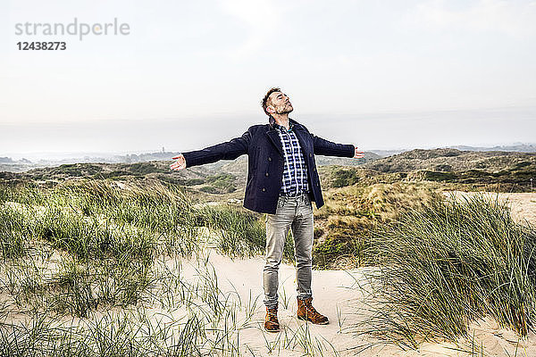Man standing in dunes with outstretched arms