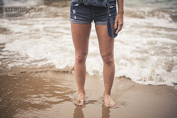 Legs of young woman in the water on a beach