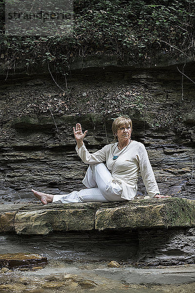 Senior woman doing yoga on rock  Half-spinal twist