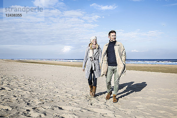 Couple in warm clothing walking on the beach