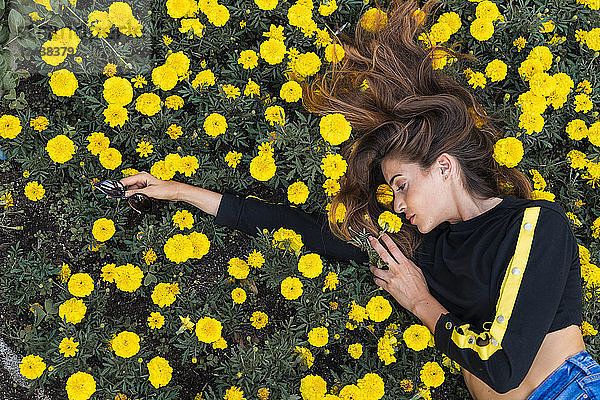 Attractive young woman lying in flower meadow