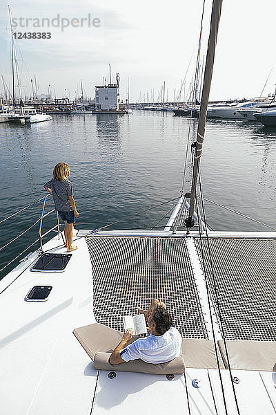 Couple on a catamaran  man sitting and reading book
