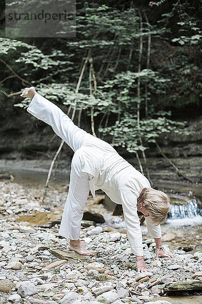 Senior woman doing yoga at brook