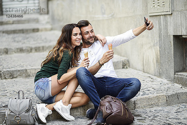Tourist couple with ice cream cones in the city taking a selfie