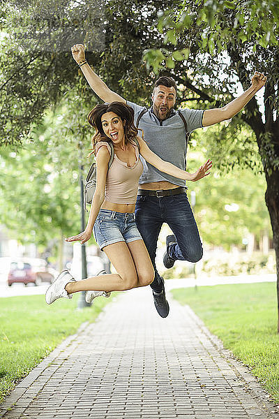 Carefree couple jumping in park