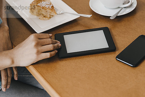 Hand of woman on table with cake and digital tablet