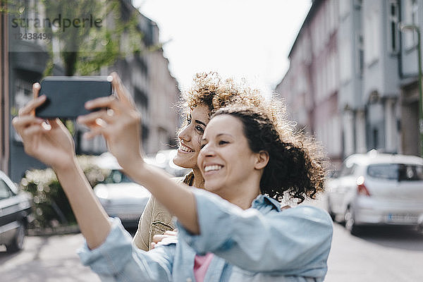 Best friends taking selfies with a smartphone in the city