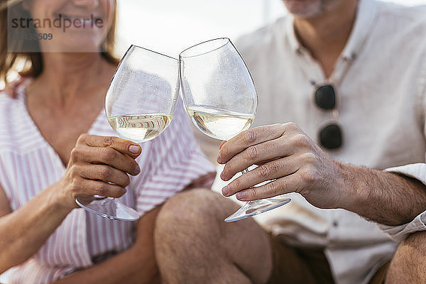 Mature couple drinking wine at sunset on a sailing boat