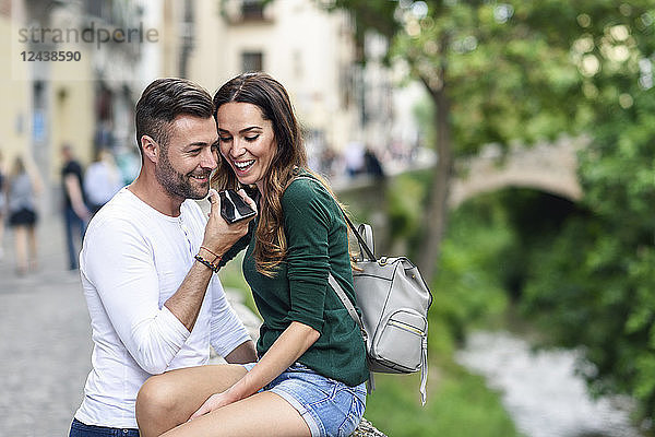 Happy tourist couple using cell phone in the city
