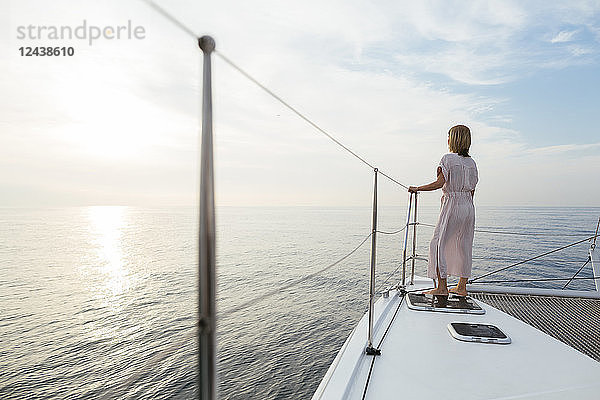 Mature woman standing on catamaran  watching sunset