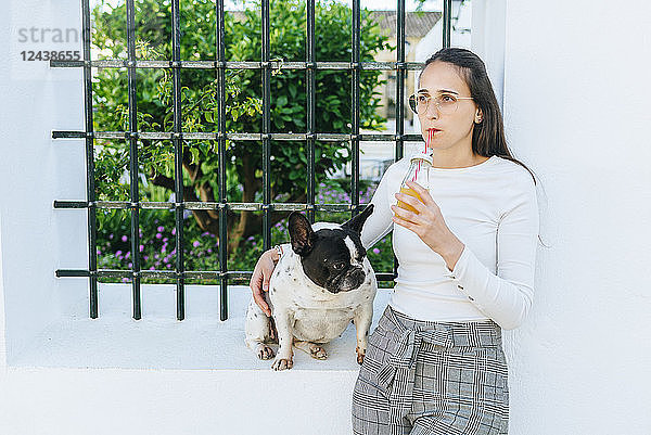 Woman drinking juice  with her dog outside