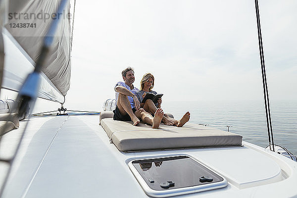 Couple sitting on deck of catamaran  relaxing  woman reading book