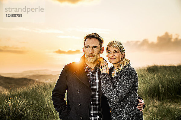 Couple standing in dunes at sunset