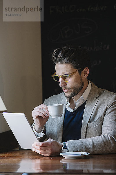 Businessman drinking coffee and using tablet in a cafe