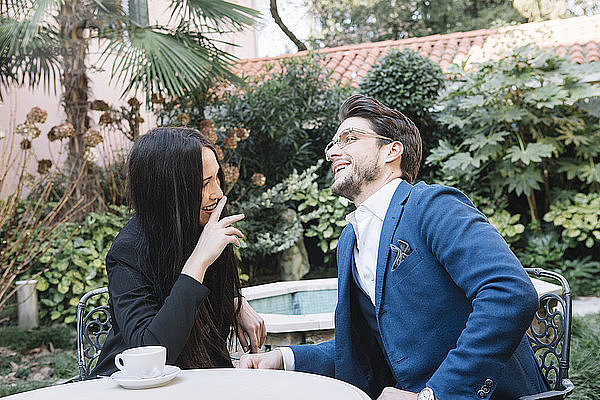 Happy elegant couple talking in a garden cafe