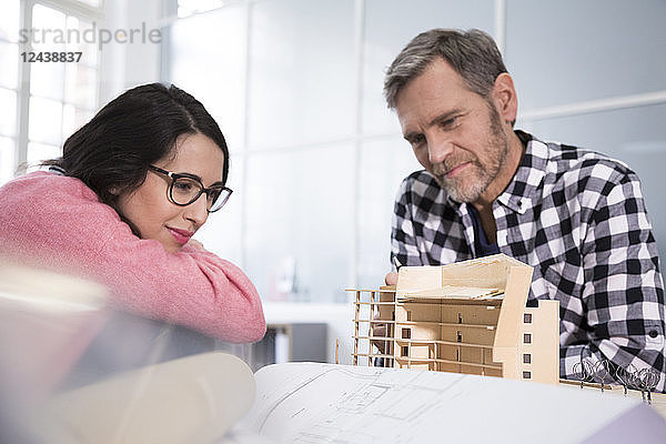 Smiling colleagues looking at architectural model in office