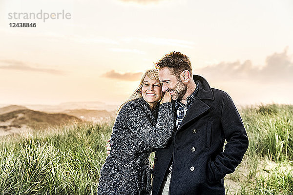 Happy couple in dunes at sunset