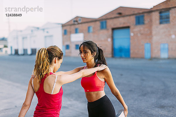 Two active women stretching and supporting each other