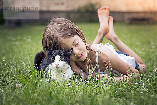 Little girl cuddling with cat on a meadow