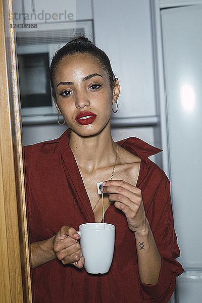 Portrait of beautiful young woman with cup of tea at home