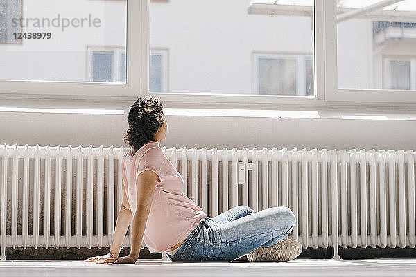 Woman sitting on ground  looking out of window