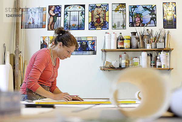 Woman working on draft in glazier's workshop