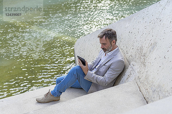 Businessman sitting on steps outdoors using tablet