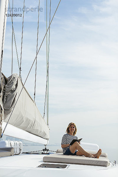 Woman sitting on deck of a catamaran  reading a book
