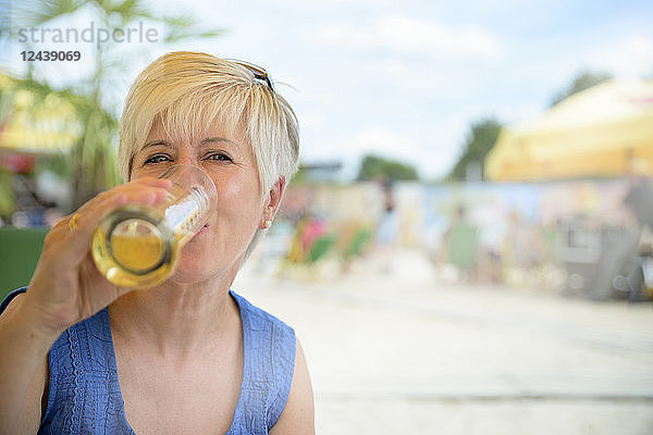 Portrait of senior woman drinking beer at beach bar