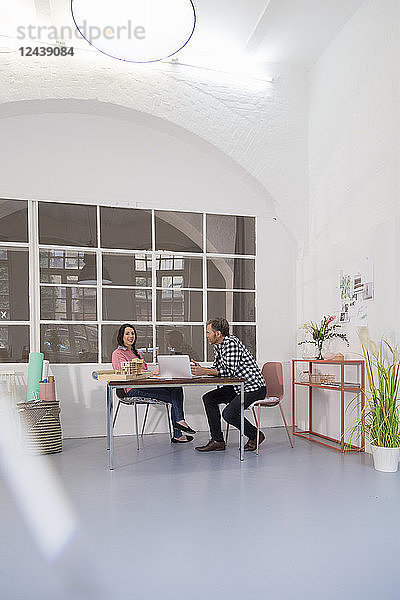 Colleagues sitting at table in an architect's loft office