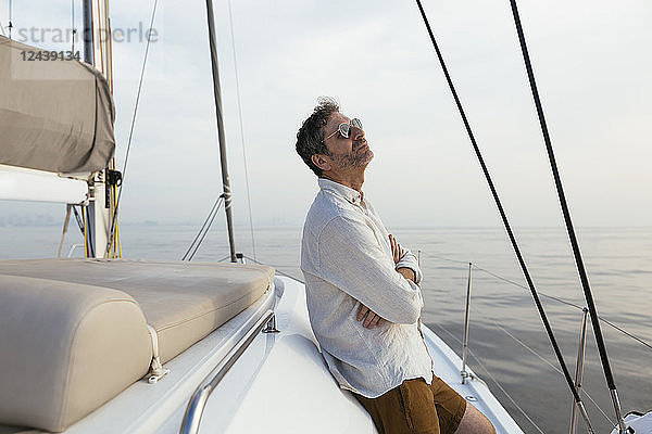 Marure man on catamaran with arms crossed  enjoying the breeze