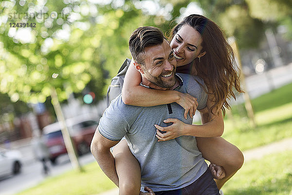 Happy man giving girlfriend a piggyback ride in park