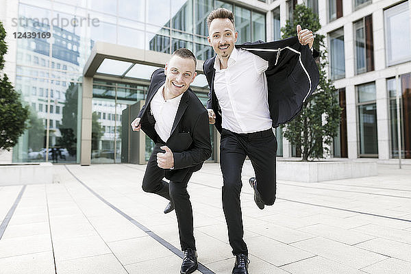 Two happy businessmen in front of office building