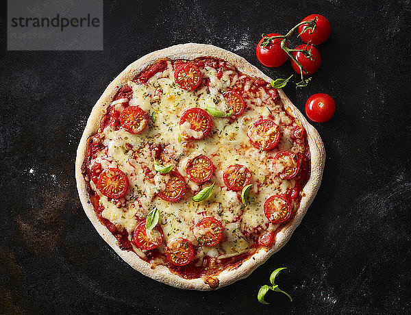 Pizza Margherita and cherry tomatoes on dark ground
