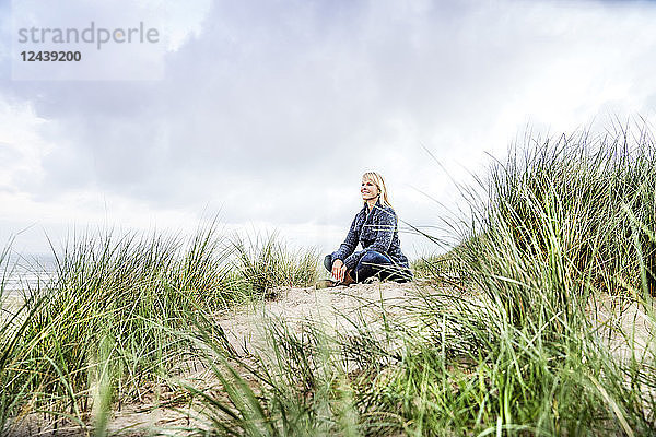 Smiling woman sitting in dunes