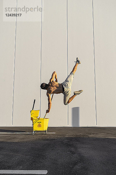 Acrobat playing with cleaning bucket and mop
