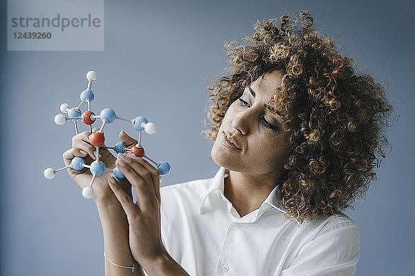 Female scientist looking at molecule model  looking for solutions