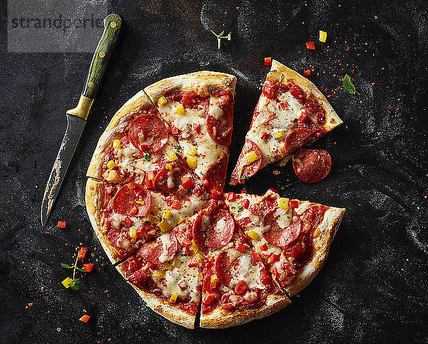 Sliced pizza with salami on dark ground